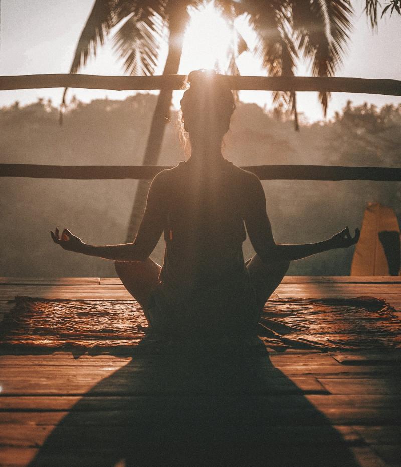 Person meditating peacefully in a natural setting at sunrise