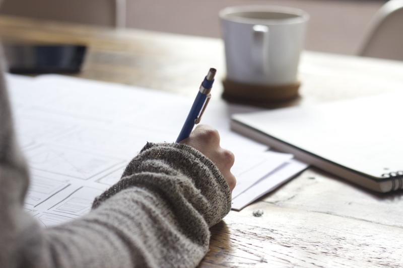 Person thoughtfully planning their business strategy with a notebook and pen